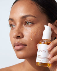 Model applying Glow Oil to her cheek