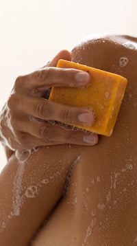 Organic Turmeric Soap Bar in use on the shoulder
